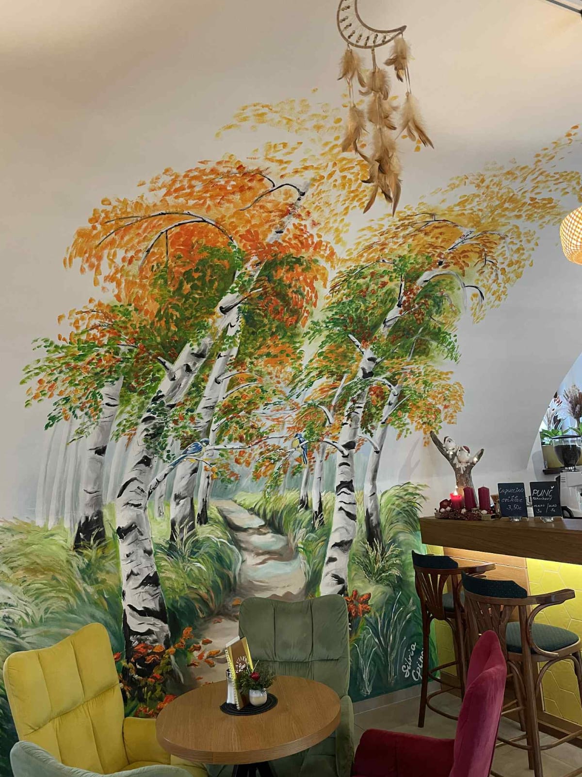 Útulný interiér kaviarne s nástennou maľbou brehového hája